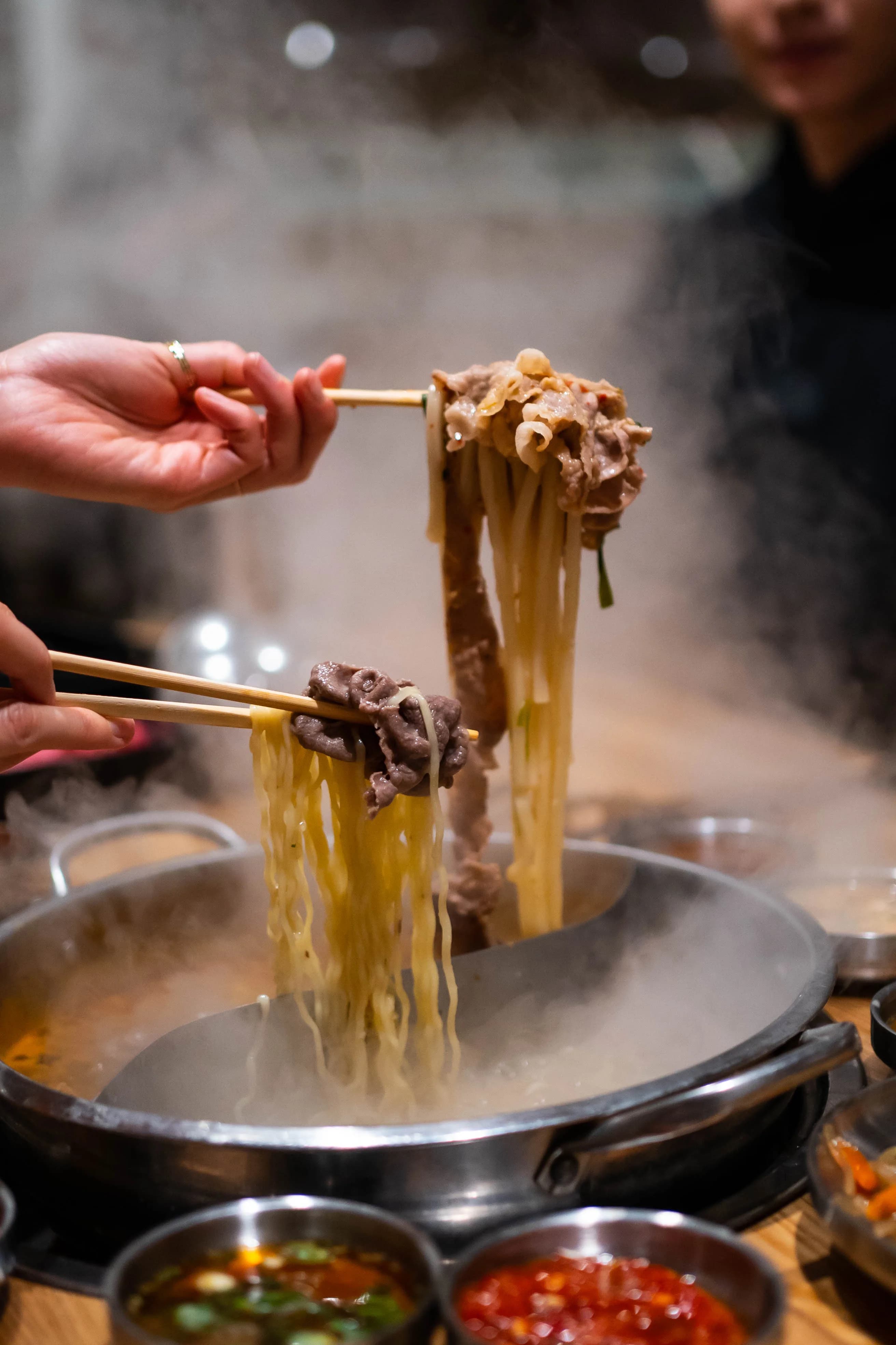 Noodles and meat lifted from steaming broth