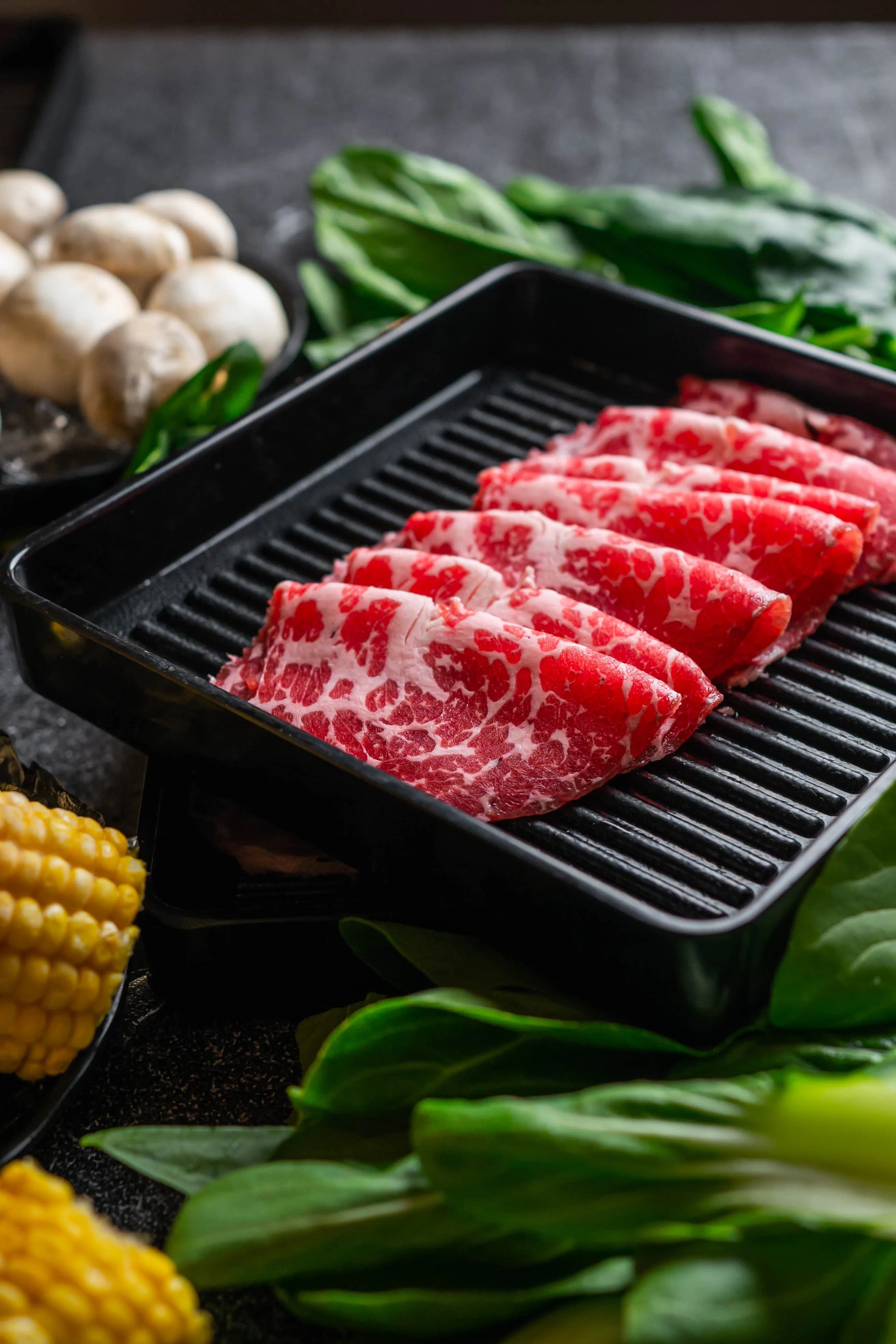 Wagyu slices on black tray with vegetables